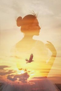 Asian woman calmly contemplating as bird flies in the distance